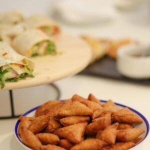 Plate of crispy mini samosas and fresh wraps served on a wooden table in Dubai.